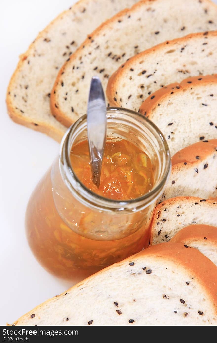 Spread slice brown wholewheat bread and orange jam on white background