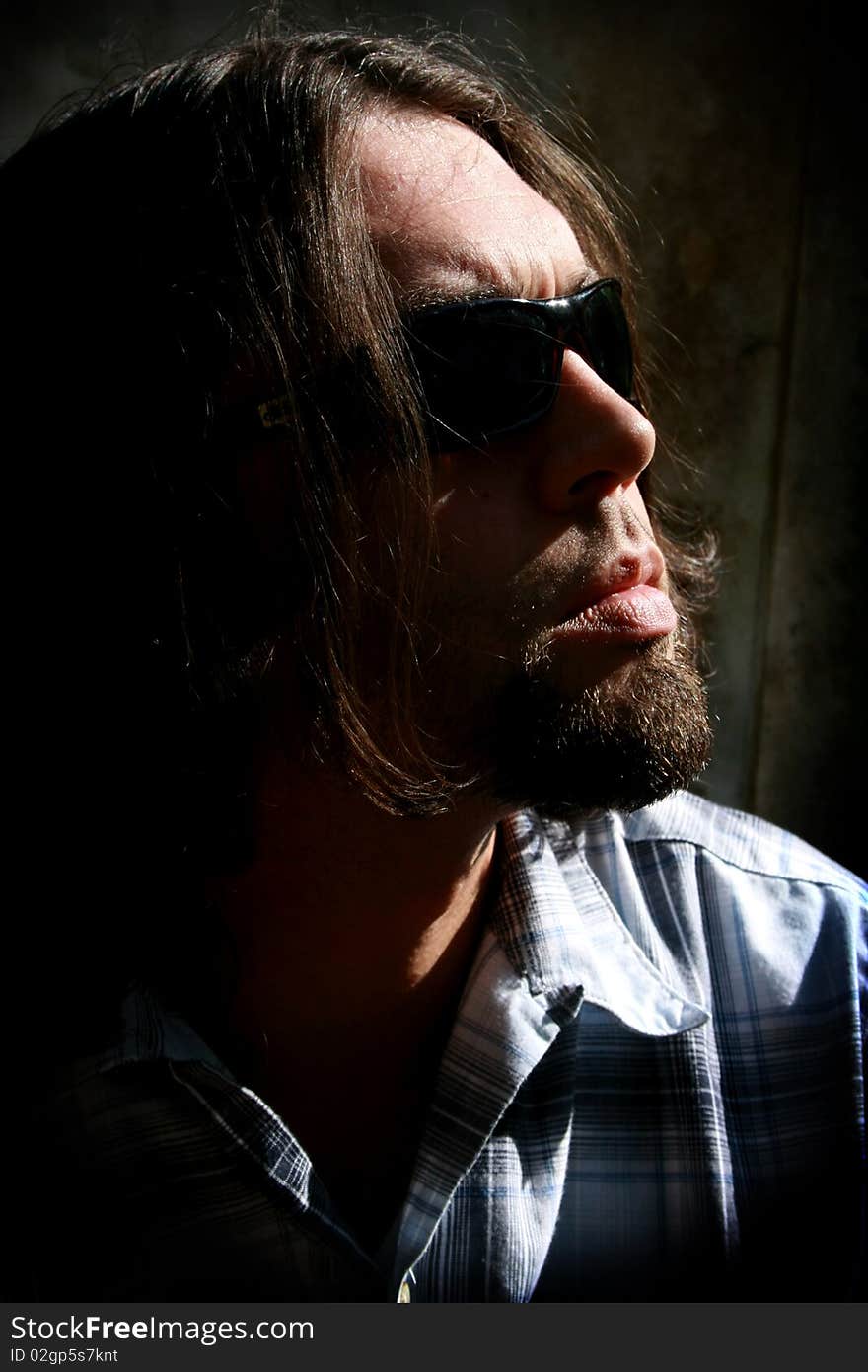 Long haired man with sunglasses in a low key shot. Long haired man with sunglasses in a low key shot