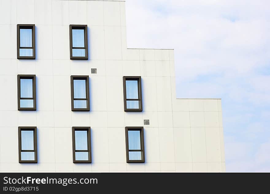 Office building detail with windows against blue sky with clouds. Office building detail with windows against blue sky with clouds.