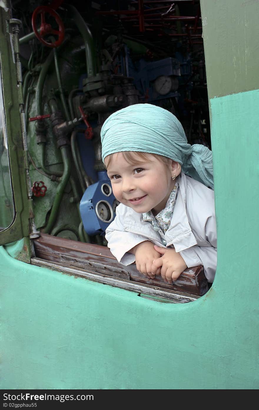 The girl looks out of the opened window of a steam locomotive. The girl looks out of the opened window of a steam locomotive