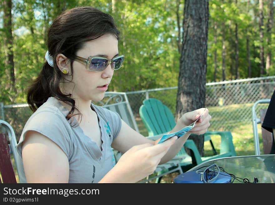 Teen girl reading cd insert with sun glasses on