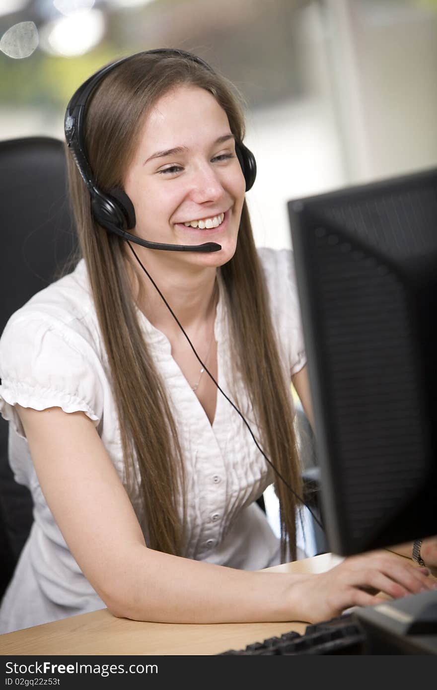 A friendly female employee answers a call at her desk. A friendly female employee answers a call at her desk.