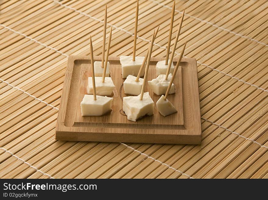 Seved white cheese on a wooden board with toothpics