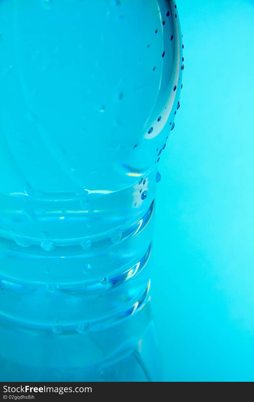 A plastic bottle filled with still water. Image isolated on light blue studio background. A plastic bottle filled with still water. Image isolated on light blue studio background.