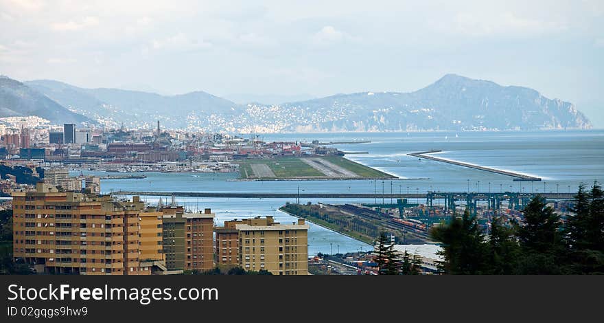 Genoa is a tourist and industry city. In this shot the industrial area of the port with freight and storage center in the background, several kilometers away, the Portofino mount, a typical seaside. Genoa is a tourist and industry city. In this shot the industrial area of the port with freight and storage center in the background, several kilometers away, the Portofino mount, a typical seaside.