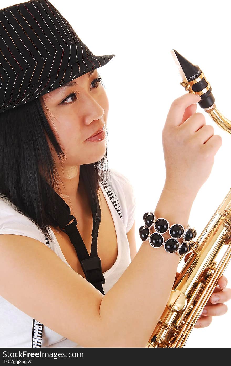 A young Asian woman with a hat on her black hair, fixing her saxophone in a closeup picture, for white background. A young Asian woman with a hat on her black hair, fixing her saxophone in a closeup picture, for white background.