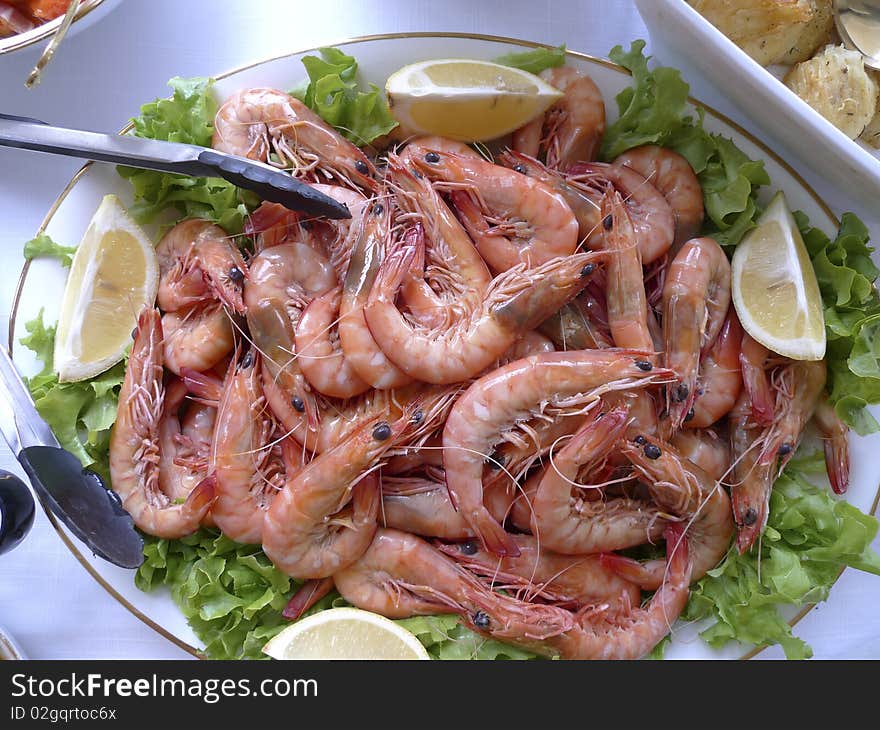 Fresh Prawns on salad leafs and lemon served in glass bowl