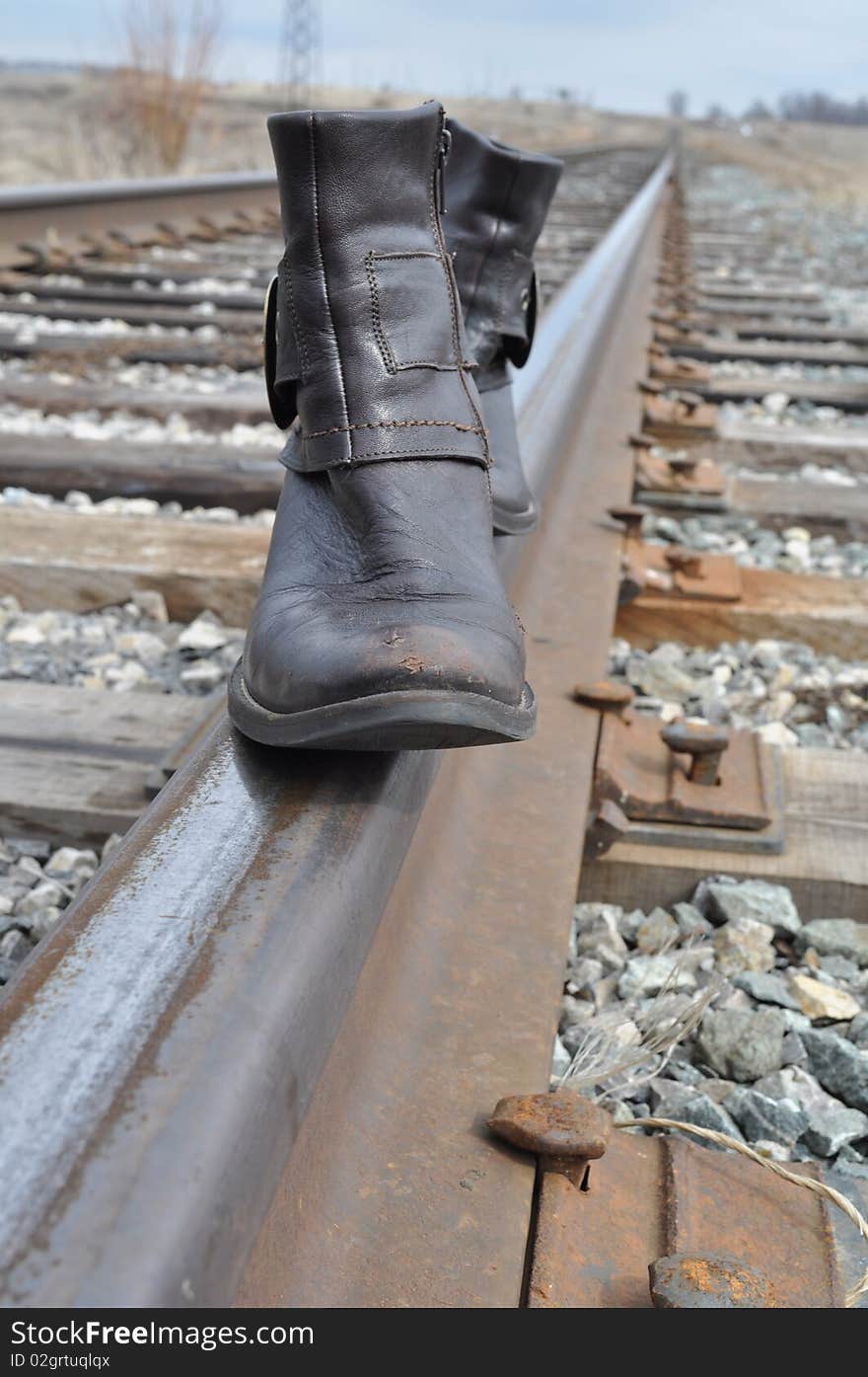 Boots with long noses are on the rails, brown and worn. Boots with long noses are on the rails, brown and worn