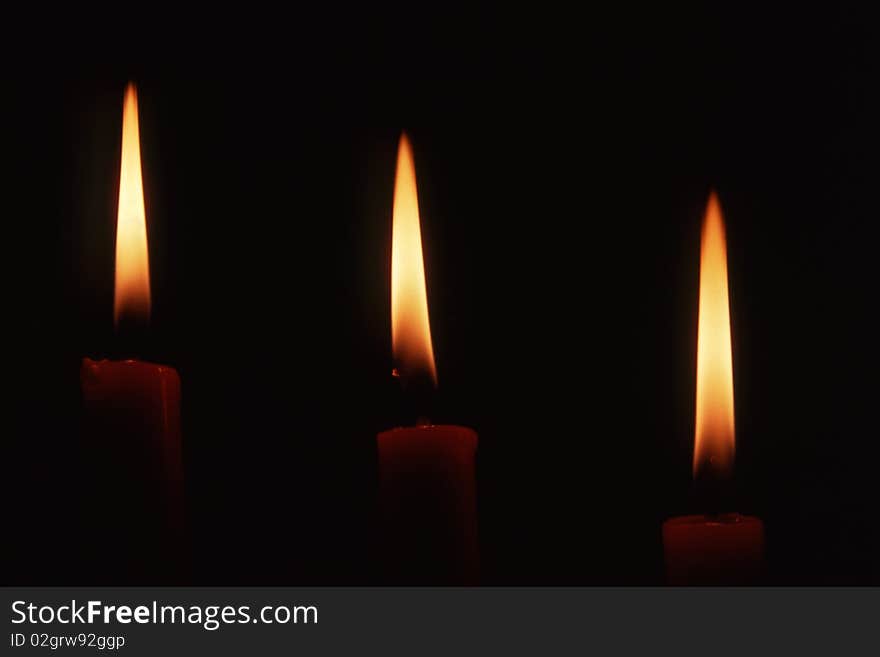 Three candles in dark background