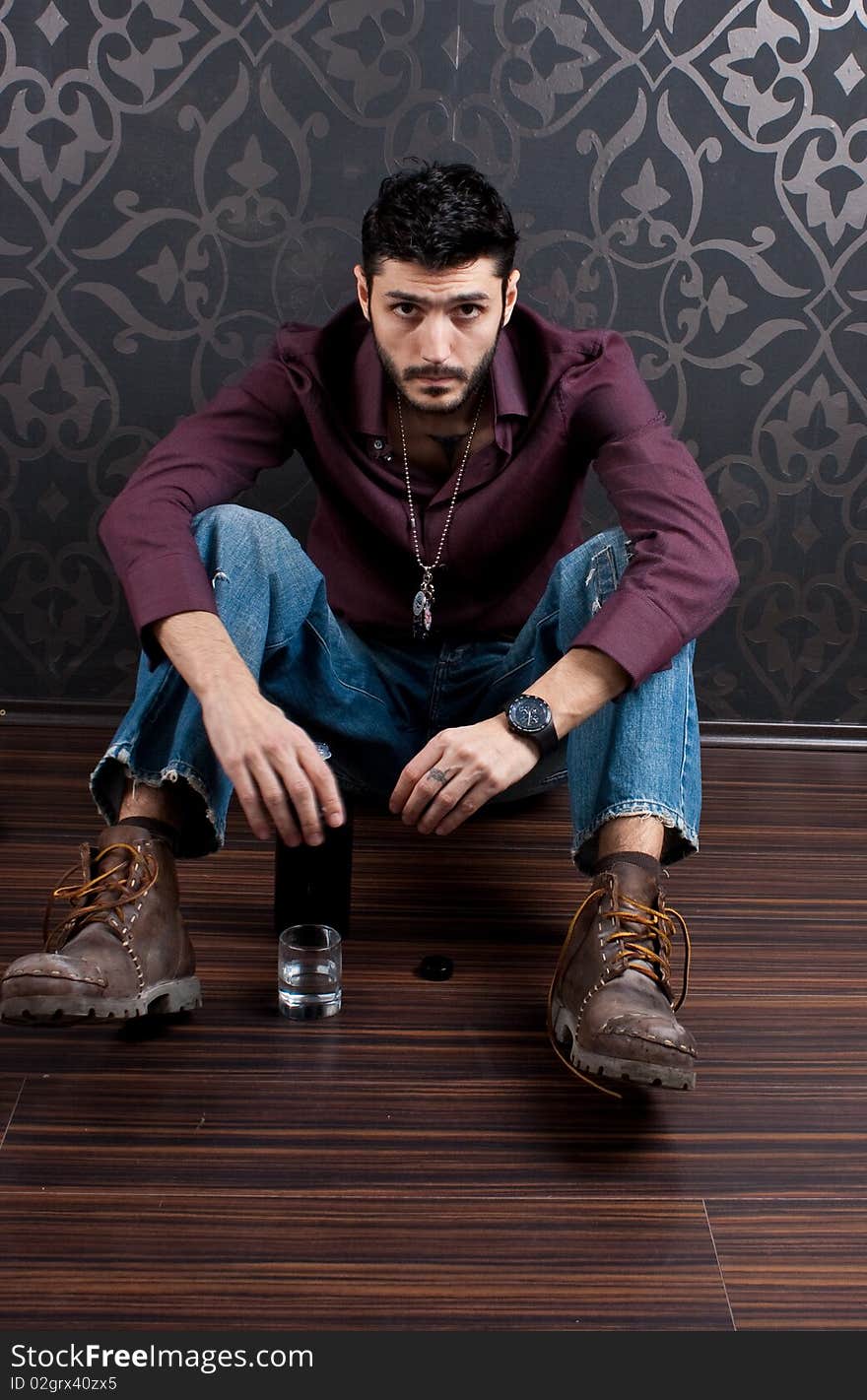 Model sitting on the floor with glass and bottle beside