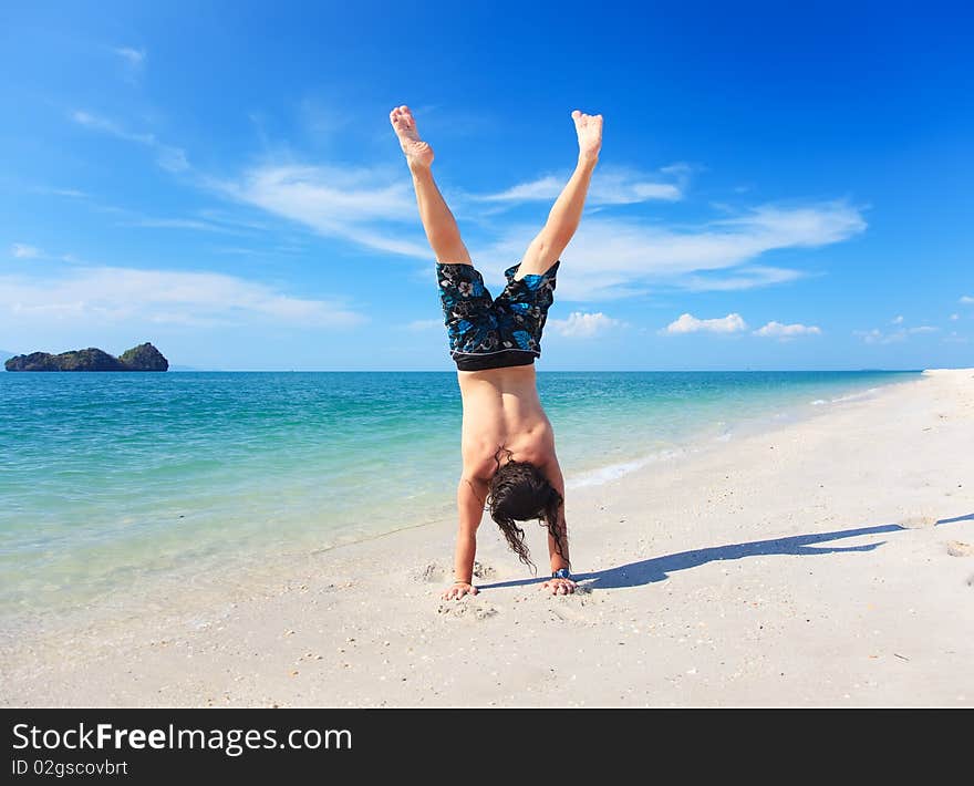 Casual guy doing the handstand on the beach