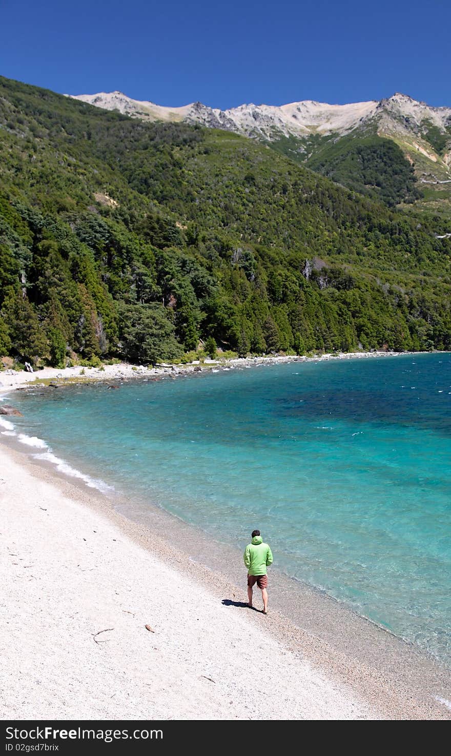 A man walking alone along the shore of a beautiful lake