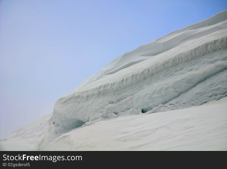 Overhanging snow ridge against blue sky