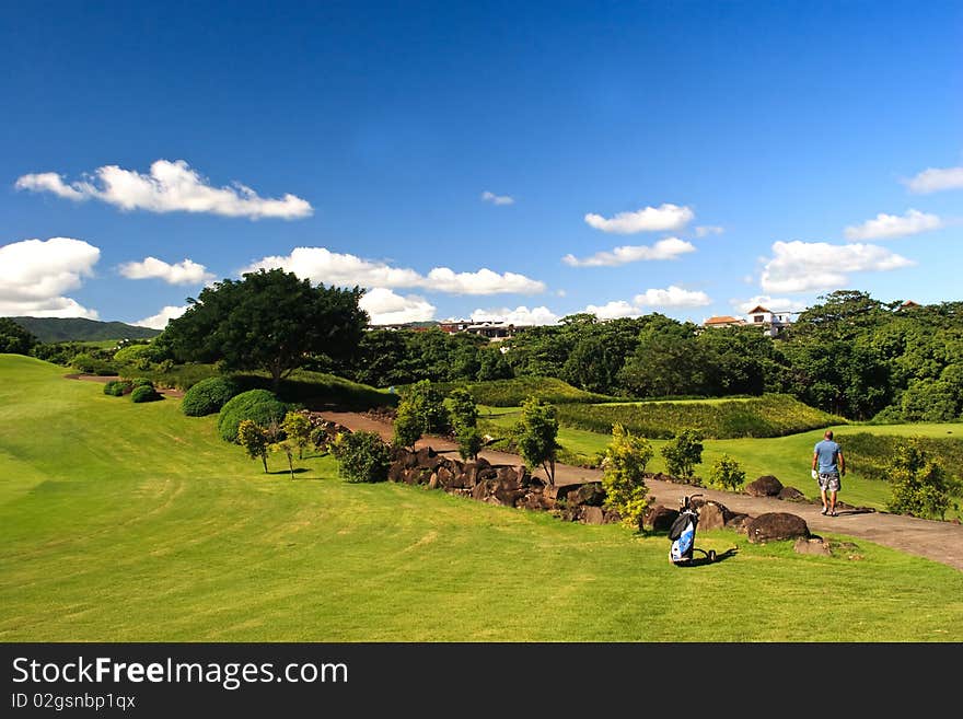 A golfer searching his ball in a beautiful greenery view of a golf field in Mauritius