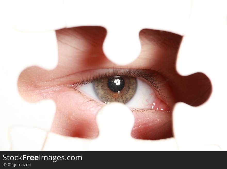 Human eye looking out through the hole in jigsaw puzzle