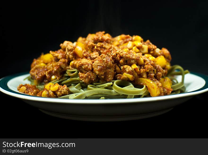 A plate of noodles and meat sauce on black background. A plate of noodles and meat sauce on black background.