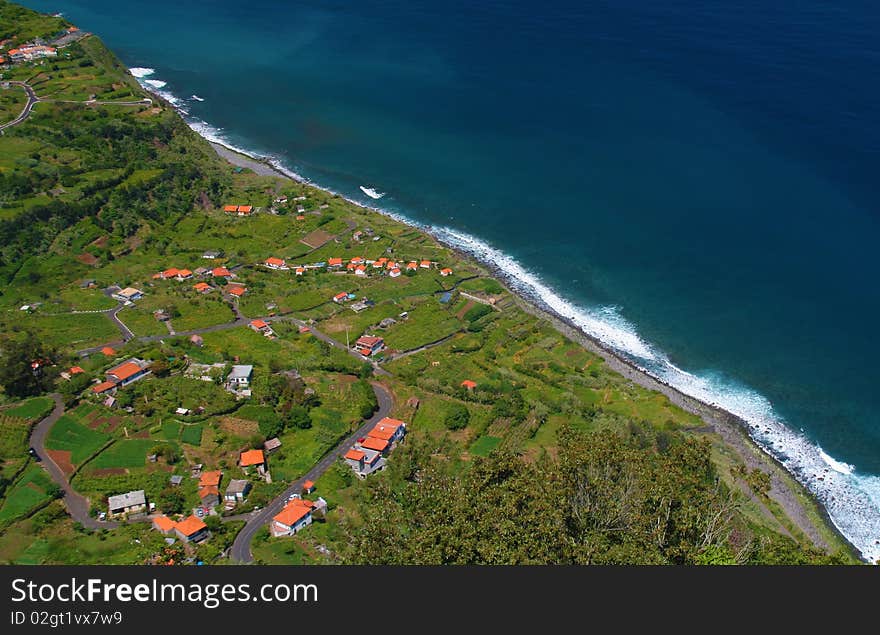 Madeira atlantic coastline with villaage and curvy roads. Half is coast and other half is ocean. Coastline divides the photo with nice diagonal.