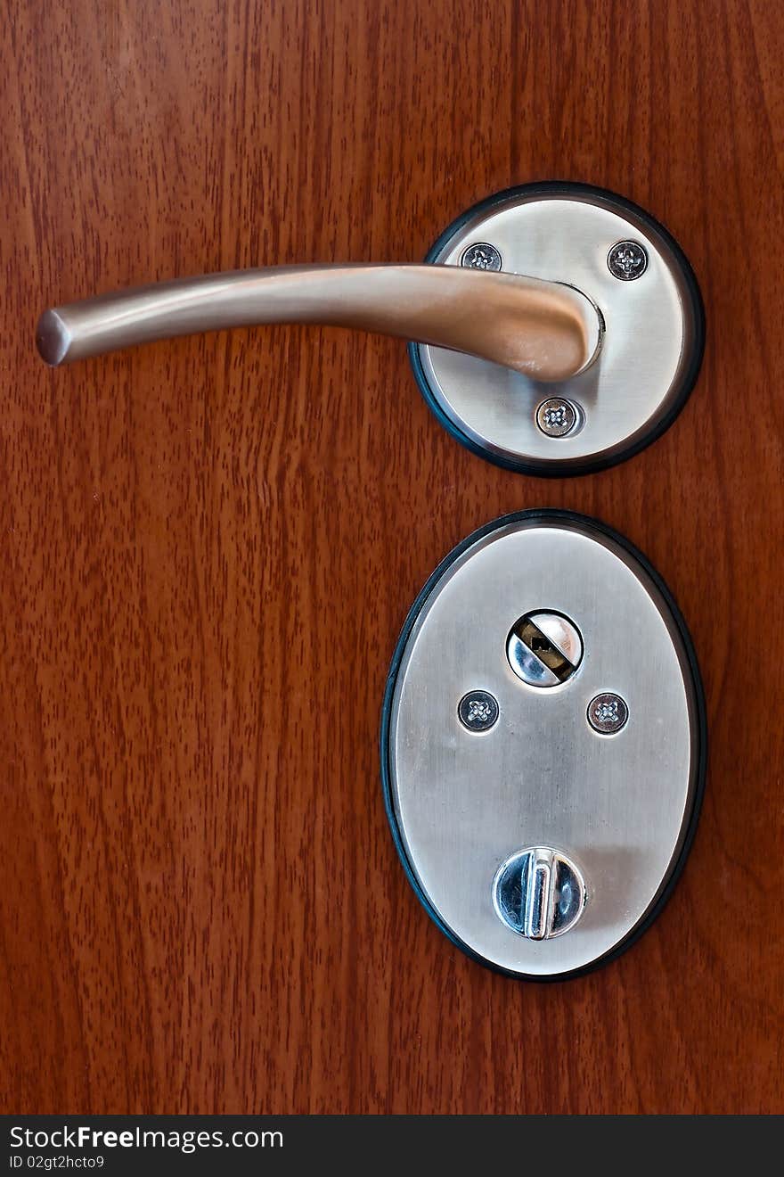 Silver door handle on brown wooden door