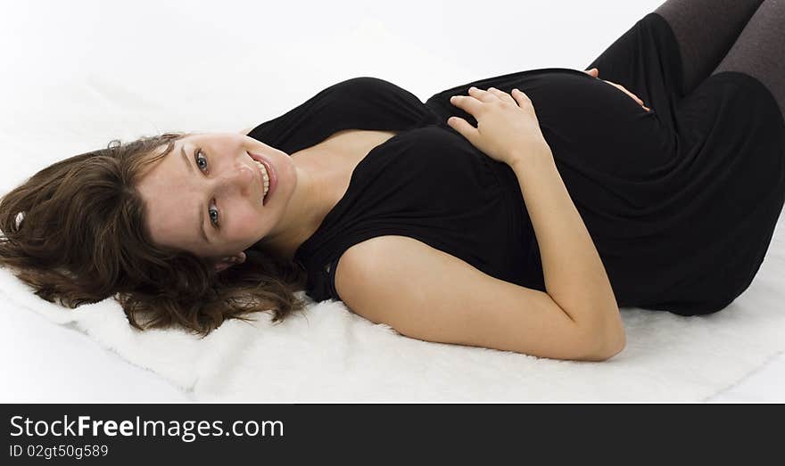 Beautiful young pregnant woman lying and smiling in black dress on white background. Beautiful young pregnant woman lying and smiling in black dress on white background