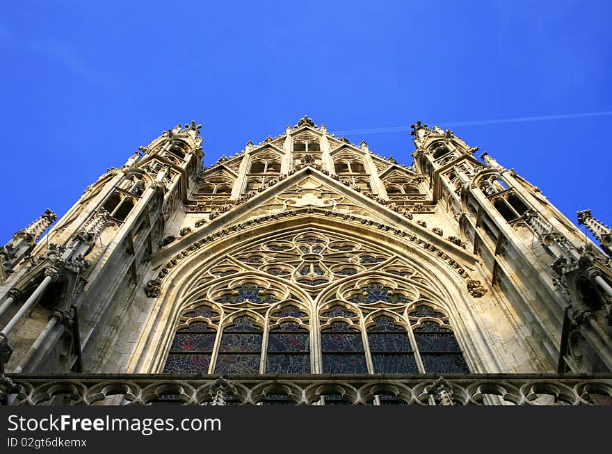 A typical Gothic Cathedral in the old medieval district of Vienna. The image shows a detail of a beautifully colored strained-glass window a trademark of the Gothic architecture. A typical Gothic Cathedral in the old medieval district of Vienna. The image shows a detail of a beautifully colored strained-glass window a trademark of the Gothic architecture.