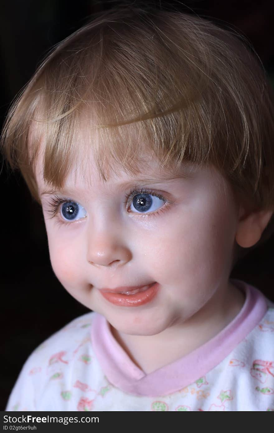 Portrait of a close-up little smiling child with big blue eyes.