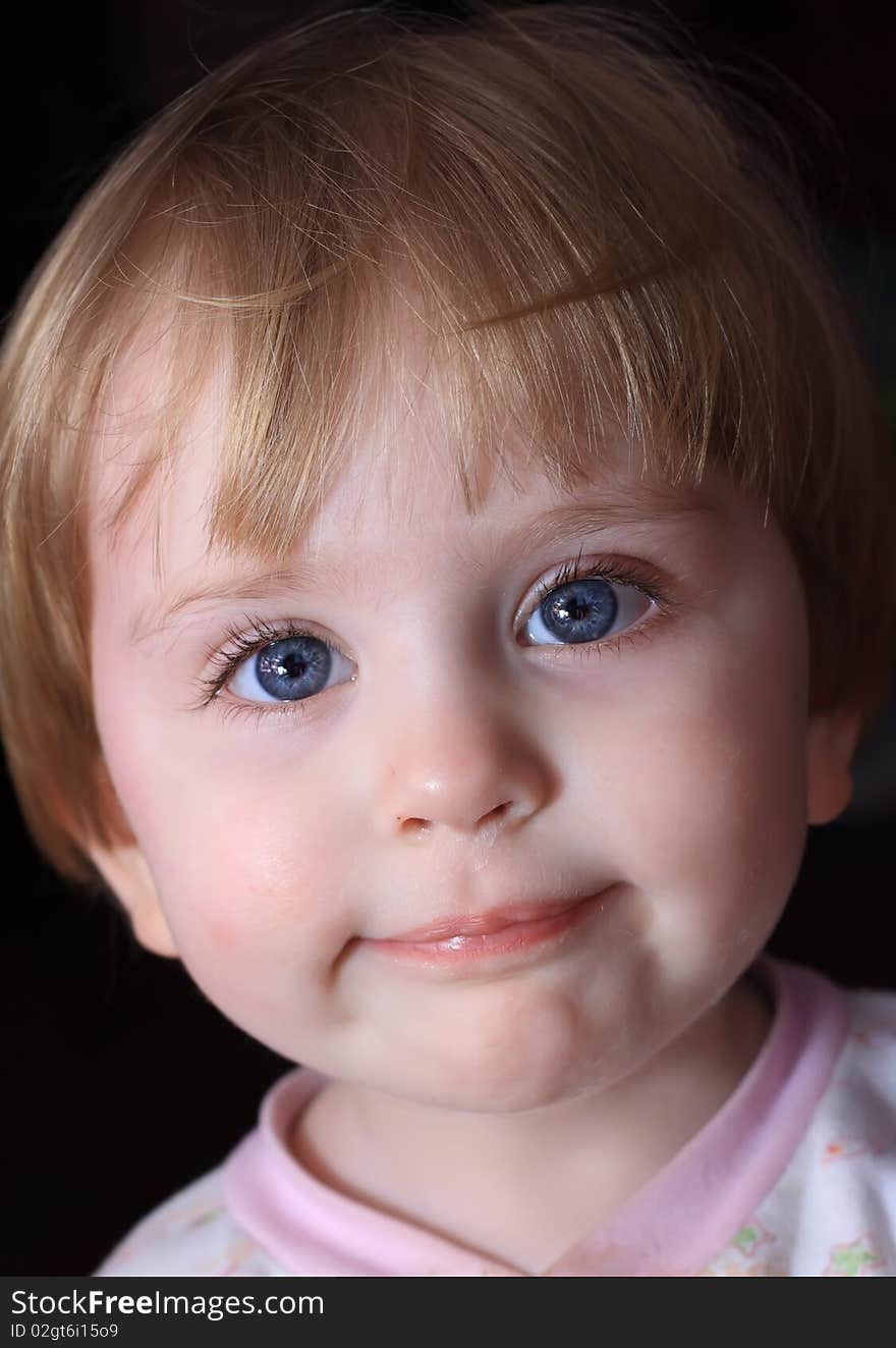 Portrait of a close-up little smiling child with big blue eyes.