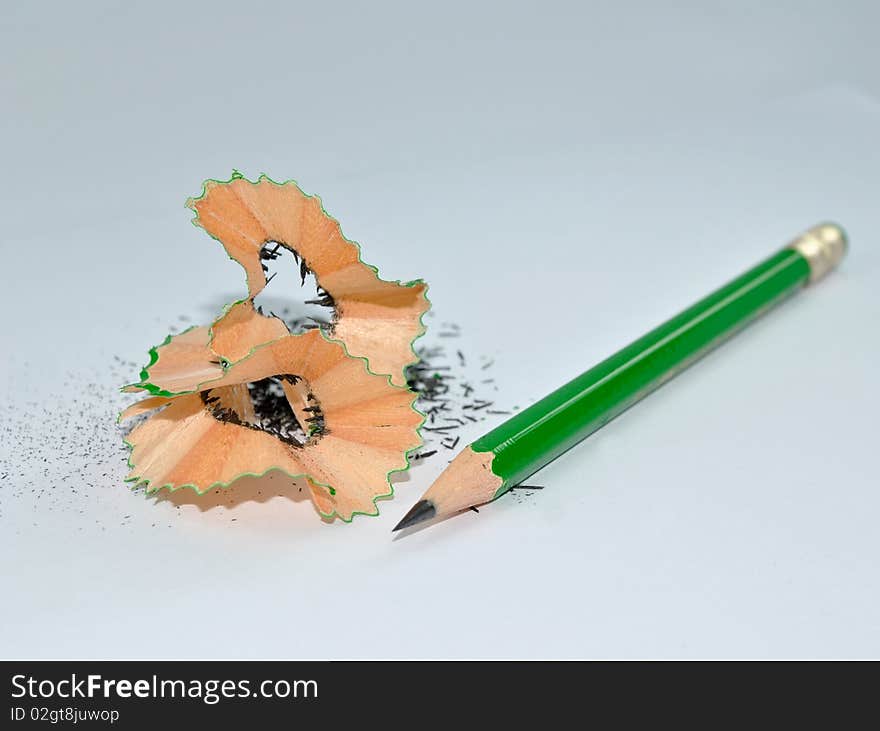 A sharpened green pencil with its shreds. A sharpened green pencil with its shreds.