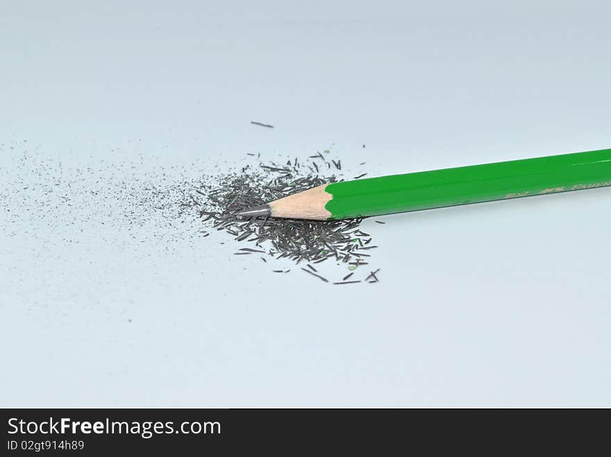 A sharpened green pencil with its shreds. A sharpened green pencil with its shreds.