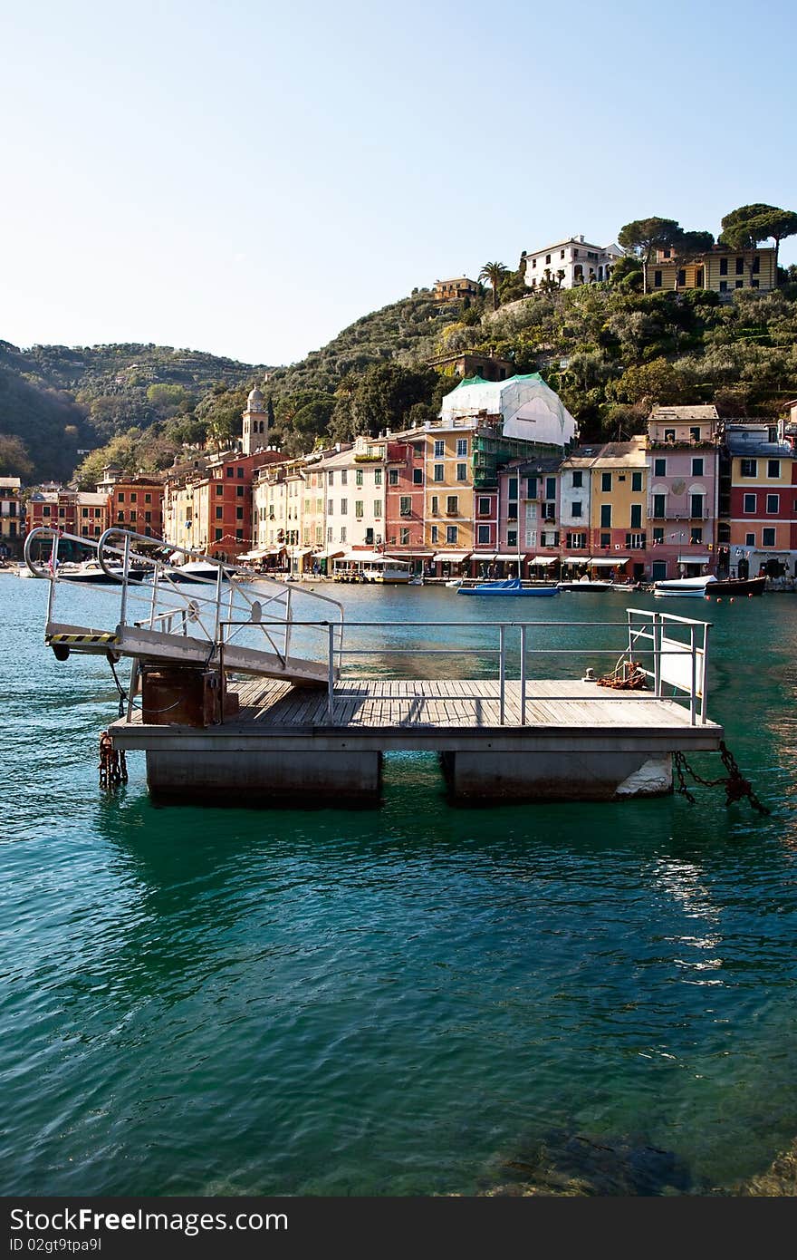 A barge and clear sea in front of the distinctive homes of the village of Portofino