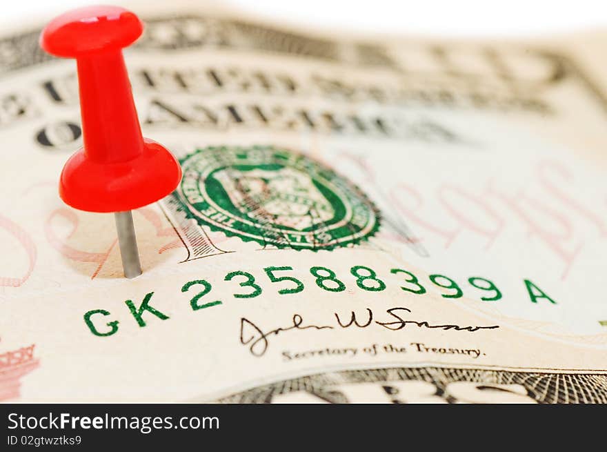 Red thumbtack on a banknote close up