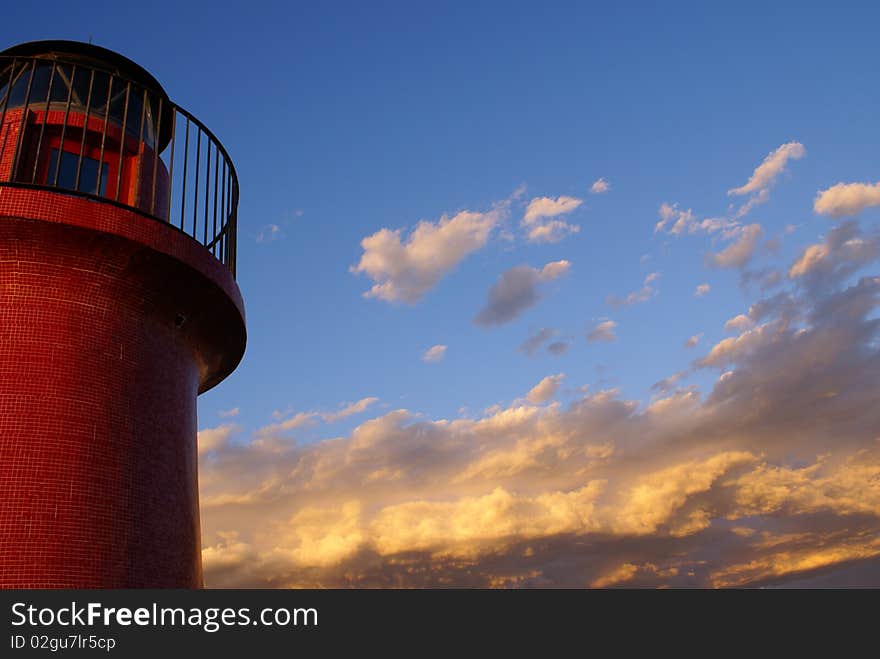 A red lighthouse and the sky with clouds to the horizon.