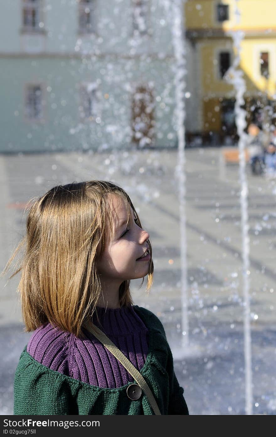 One child admiring drops fountain in city square