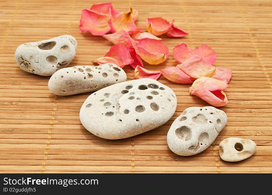 Stones and rose petals on the bamboo mat. Stones and rose petals on the bamboo mat