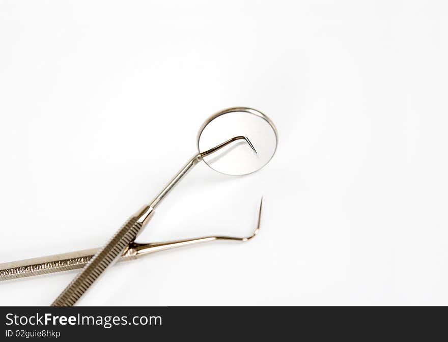 Dental mirror and pick isolated in white. Dental mirror and pick isolated in white