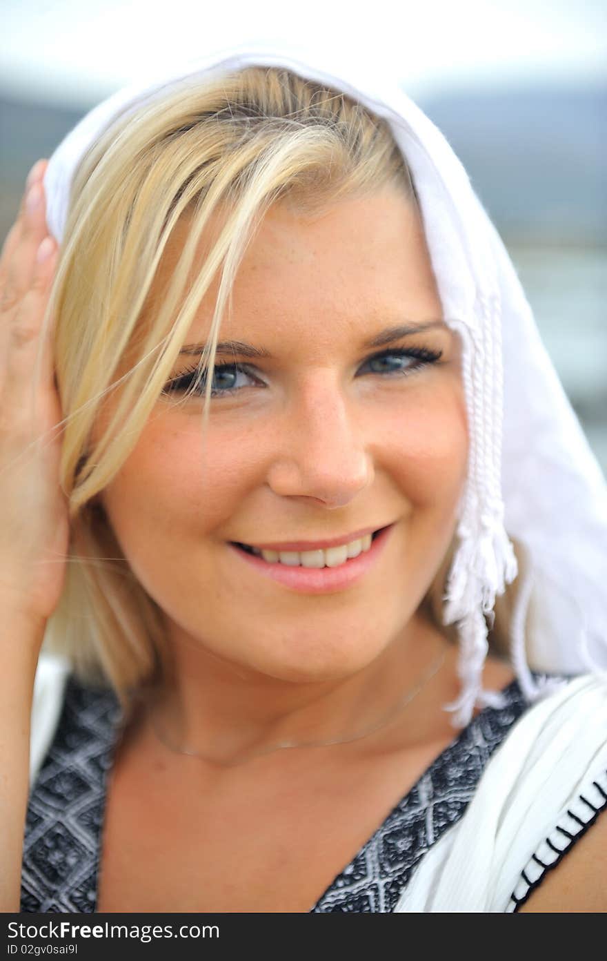 Young beautiful romantic woman in white dress dancing with shawl near blue sea