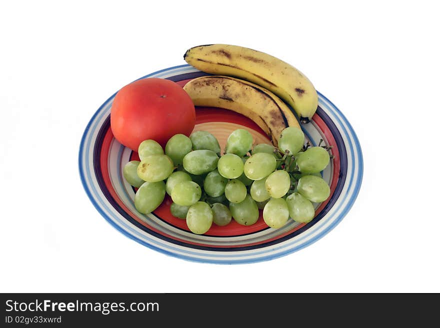 White grapes, bananas and tomato on a plate isolated on a white background