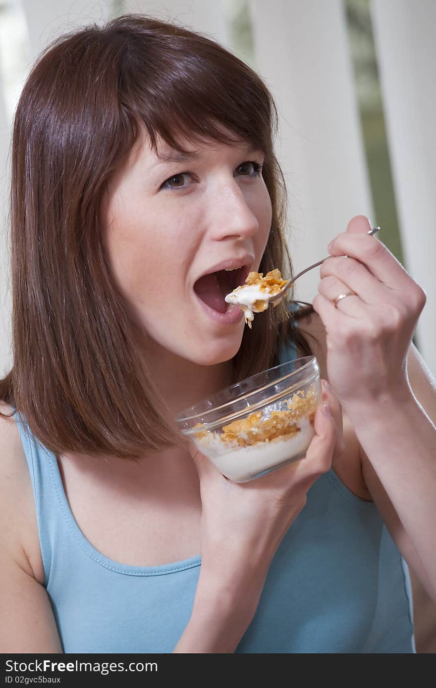 Smiling woman eating corn flakes at home on the sofa