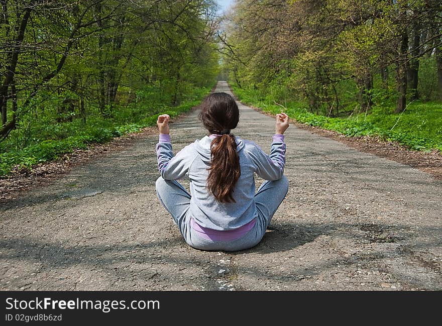 Girl sitting in the middle of the forest road