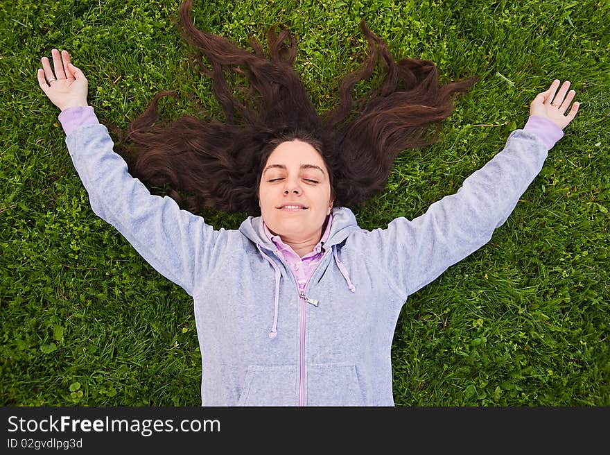 Young woman, lying on the fresh green grass, enjoying outdoors. Young woman, lying on the fresh green grass, enjoying outdoors