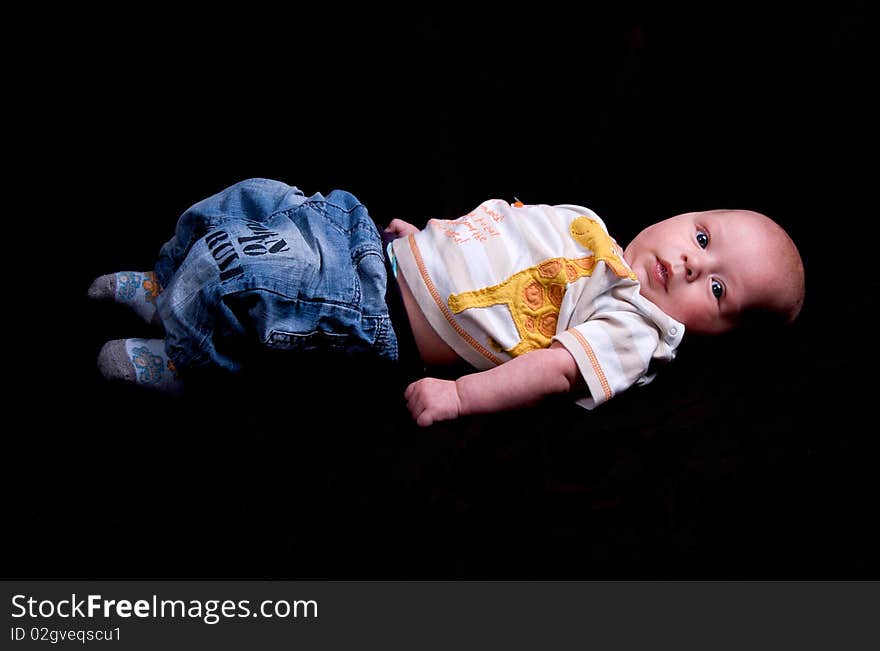 3 Month old baby lying clothed on a black background