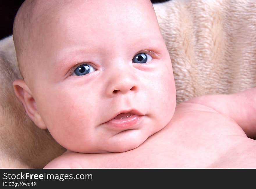 3 Month old baby lying on a fluffy blanket on a black background