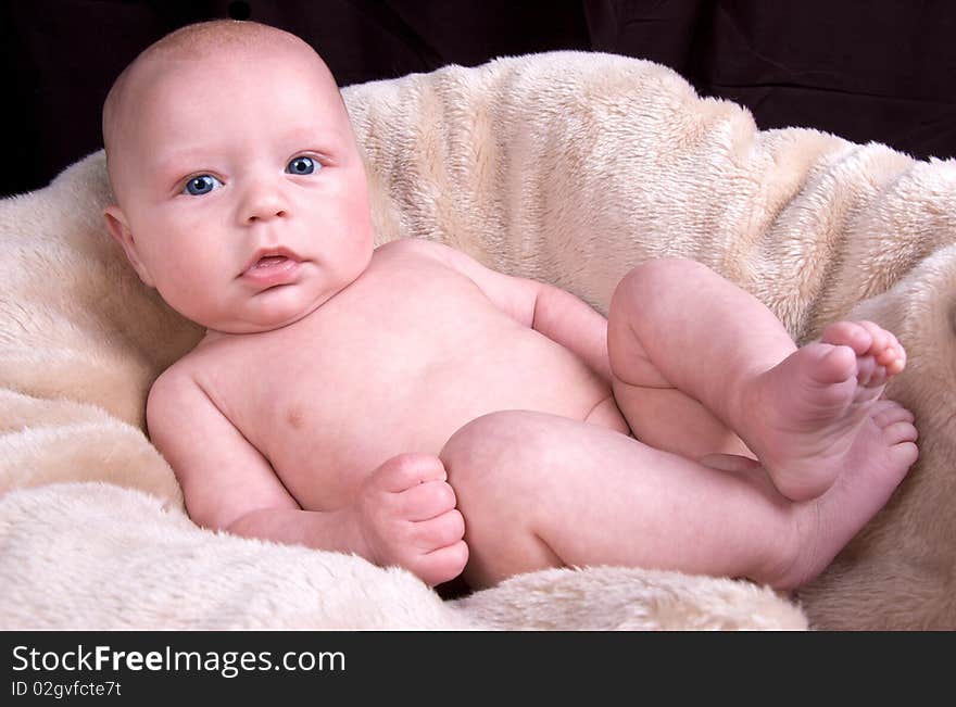 3 Month old baby lying on a fluffy blanket on a black background