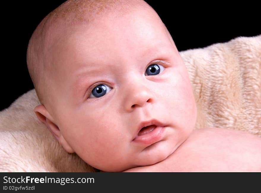 3 Month old baby lying on a fluffy blanket on a black background