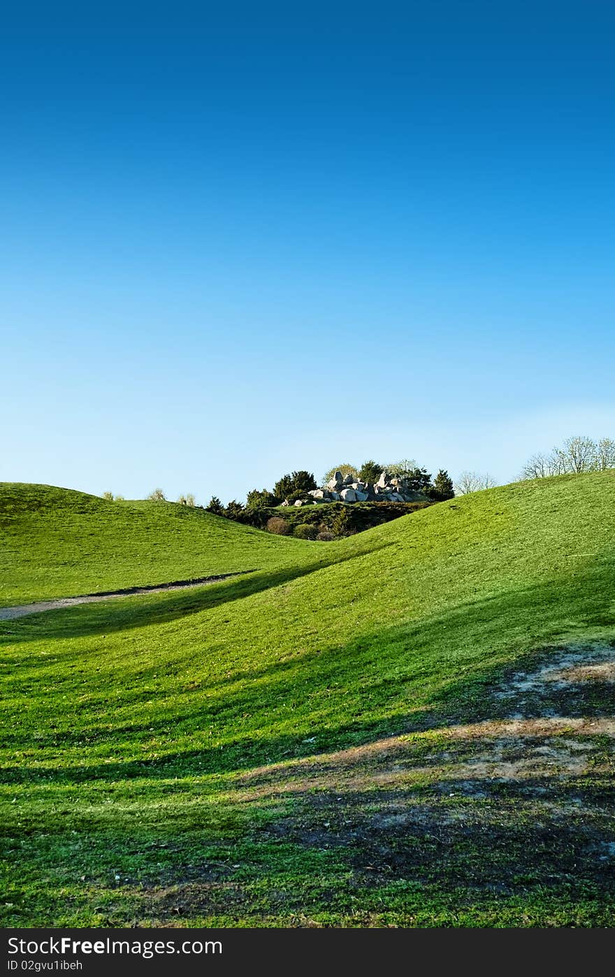 Large stones composition among green grass hills ander blue sky. Large stones composition among green grass hills ander blue sky