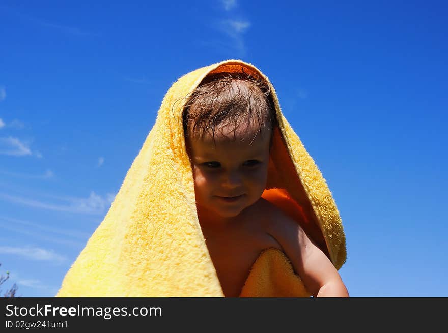 Charming little girl in a yellow towel on the beach as a symbol of childhood happiness and joy