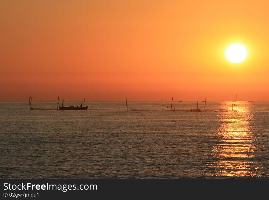 Fishermen throwing their nets in the black sea in the morning while the sun is rising above. Fishermen throwing their nets in the black sea in the morning while the sun is rising above