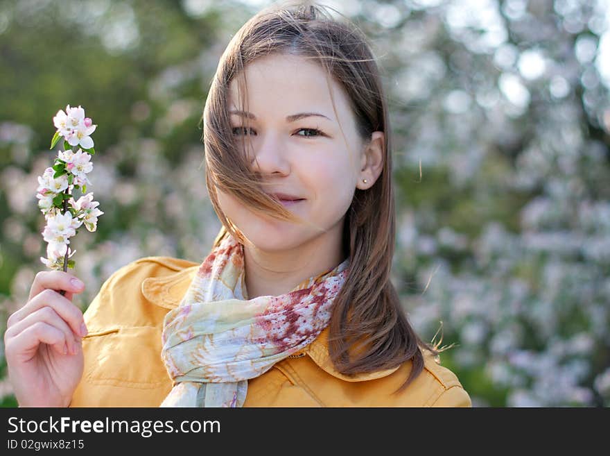 Young woman posing with a blooming branch in a spring park. Young woman posing with a blooming branch in a spring park