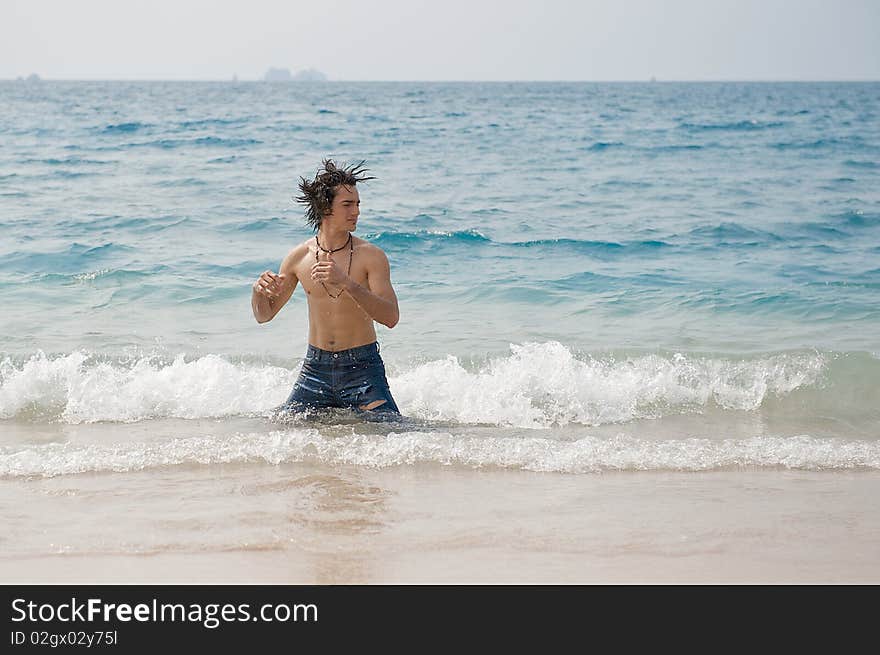 Athletic and muscular man in the surf of the Pacific Ocean shaking his wet hair. Athletic and muscular man in the surf of the Pacific Ocean shaking his wet hair.