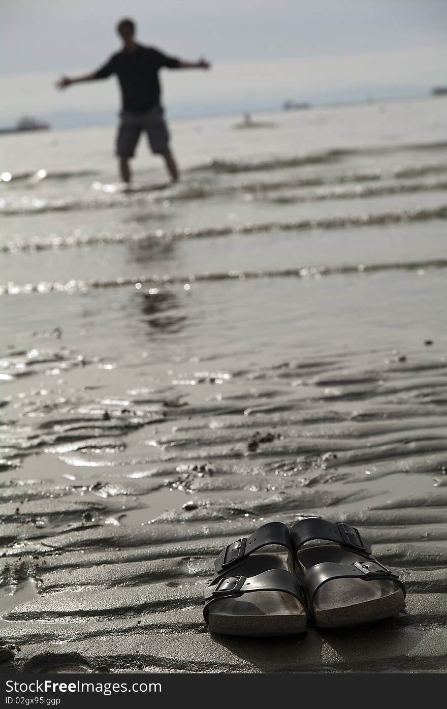 A man walking into the ocean leaving his sandles behind. A man walking into the ocean leaving his sandles behind.