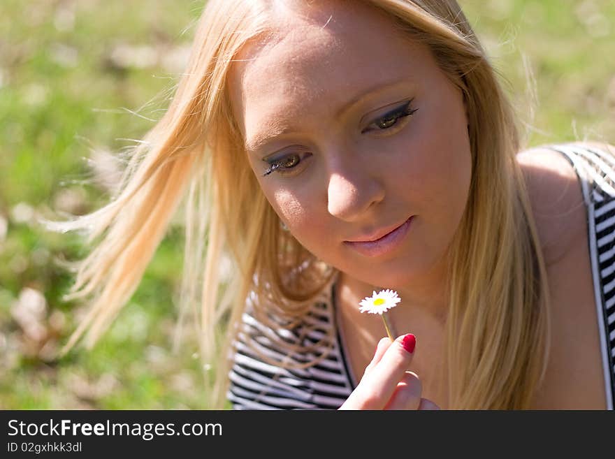 Blond girl in nature holding Daisy flower